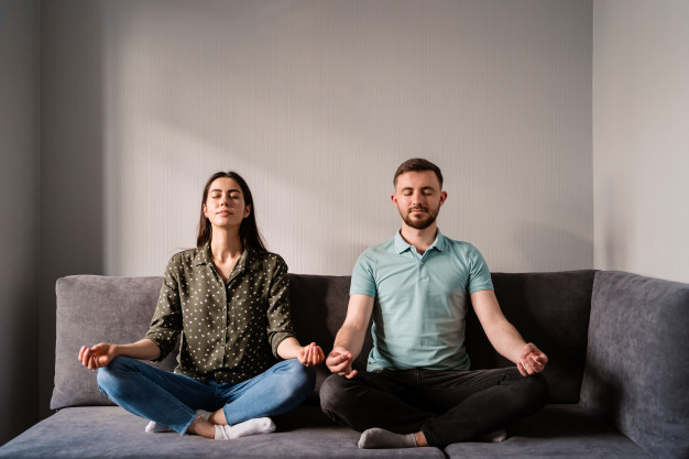 couple méditant dans le salon sur un canapé idées reçues de la méditation